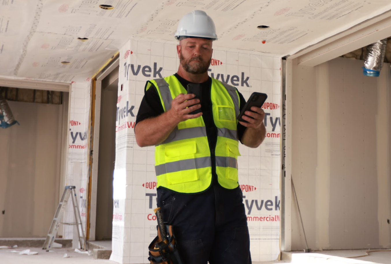 Contractor checking a handheld laser distance measure inside a building under construction