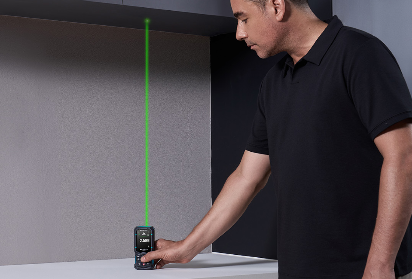 DIYer measuring vertically from a tabletop with a MILESEEY green-beam laser distance measure